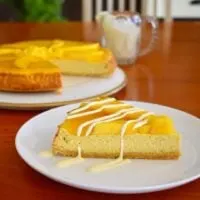 slice of baked mango cheesecake served with drizzled cream