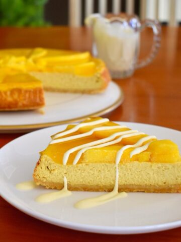 slice of baked mango cheesecake served with drizzled cream
