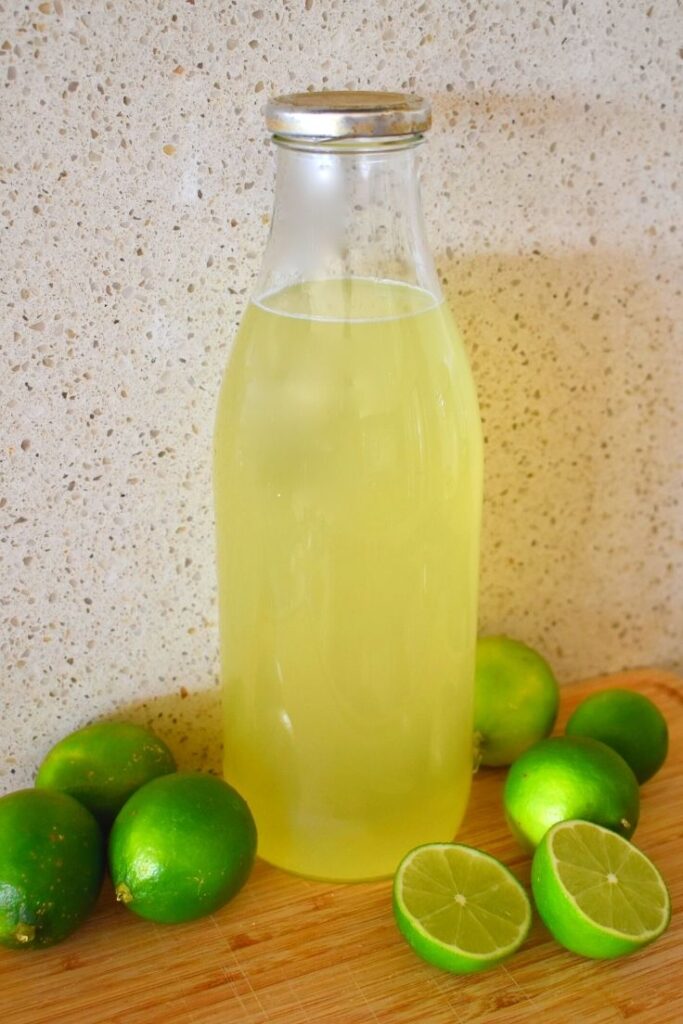 lime cordial in bottle surrounded by limes
