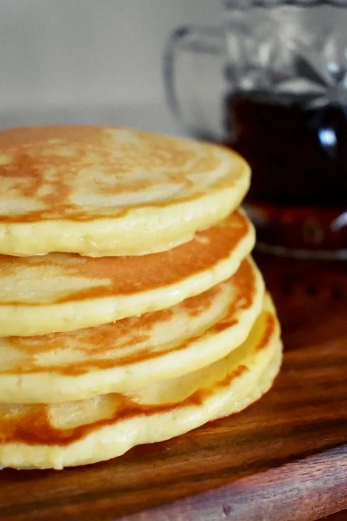 scotch pancakes with jug of maples syrup in background