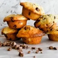 banana choc chip muffins stacked with choc chips scattered in foreground