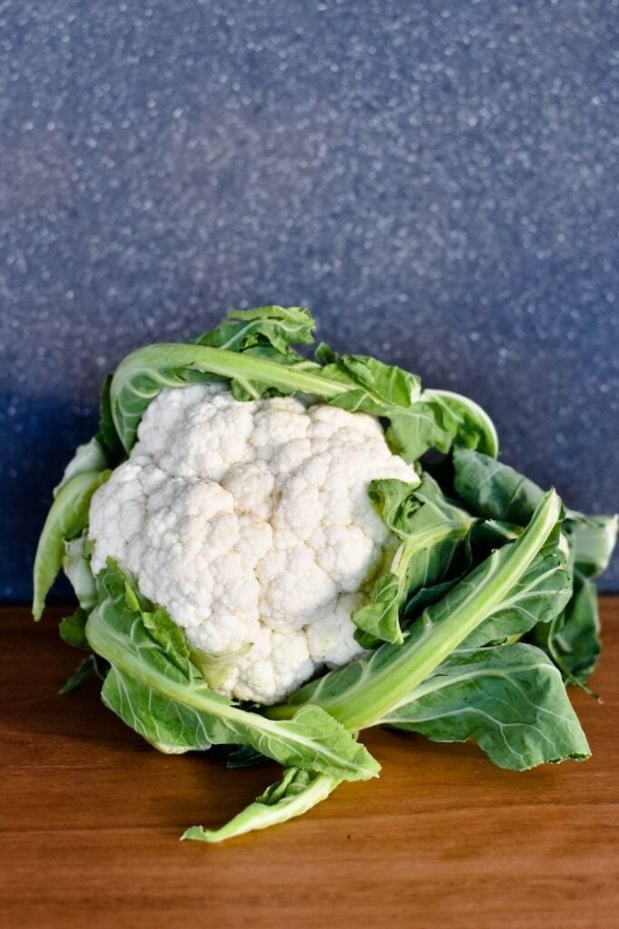 whole head of cauliflower sitting on bench