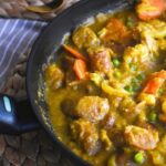 curried sausages in a black frypan.