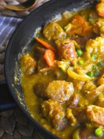 curried sausages in a black frypan.