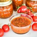 Tomato Relish in dish with jars in abckground.