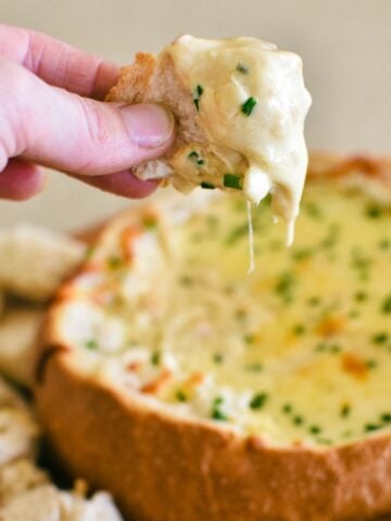 cob loaf recipe with bread dipping into cob loaf.