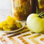 green tomato pickles with green tomato at side of dish.