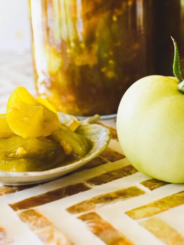 green tomato pickles with green tomato at side of dish.