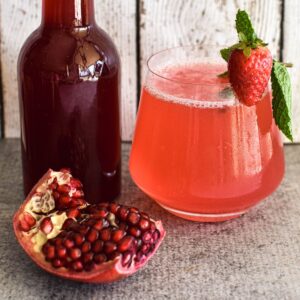 pomegranate cordial in bottle with drink using cordial.