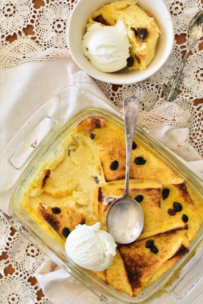 bread and butter pudding served in a bowl with ice cream.