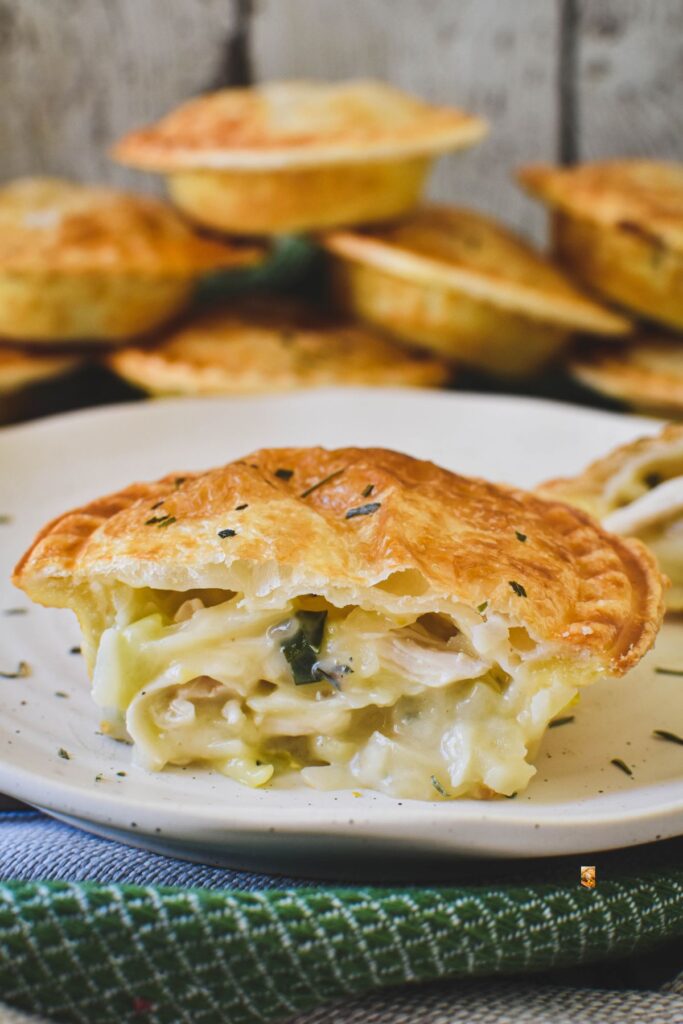 chicken and leek pie cut open with pies stacked in backround.