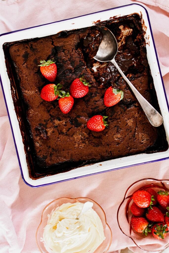 Chocolate self-sauce pudding in a casserole dish and served with strawberries.