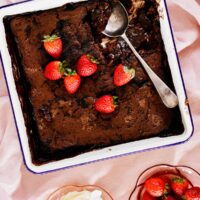 Chocolate pudding with sauce served with strawberries and whipped cream.