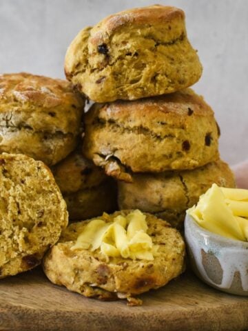 date scones on wooden board with butter in small condiment container.