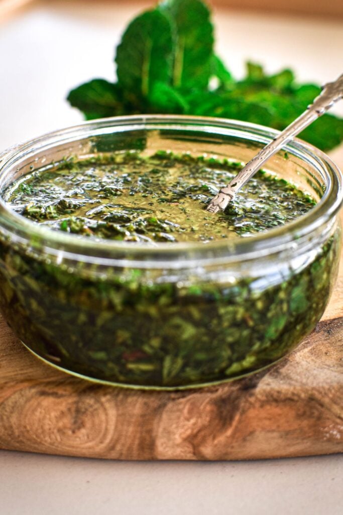 mint sauce in jar on wooden board.