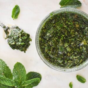 mint sauce in dish surrounded by mint leaves.