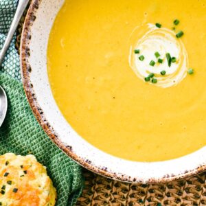 pumpkin soup in bowl garnished with cream and chives.