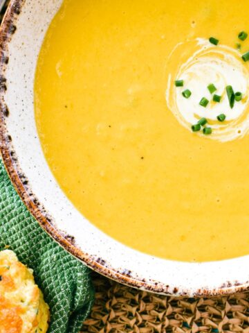 pumpkin soup in bowl garnished with cream and chives.