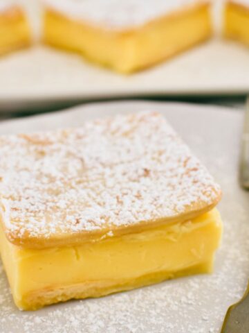 custard slice on plate dusted with icing sugar.