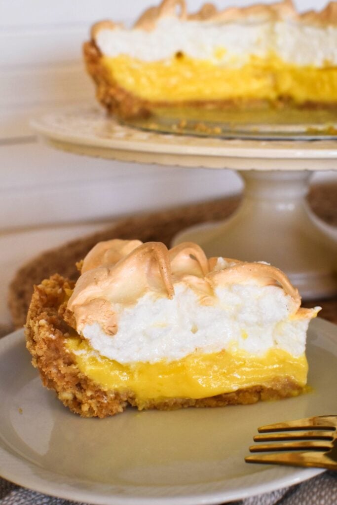 lemon meringue pie slice with whole pie in background.