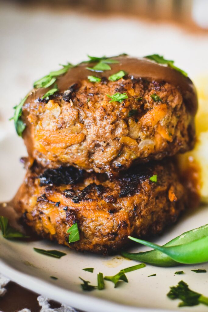 rissoles stacked on plate and served with beans and mash.