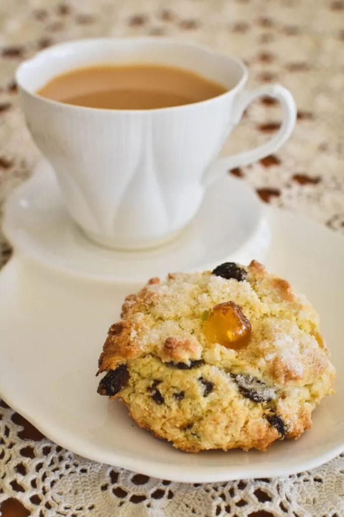 rock cake on plate with cup of tea in background.
