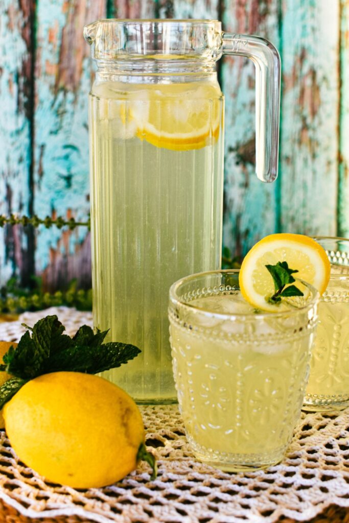 homemade lemonade in jug and glass served with ice and mint.