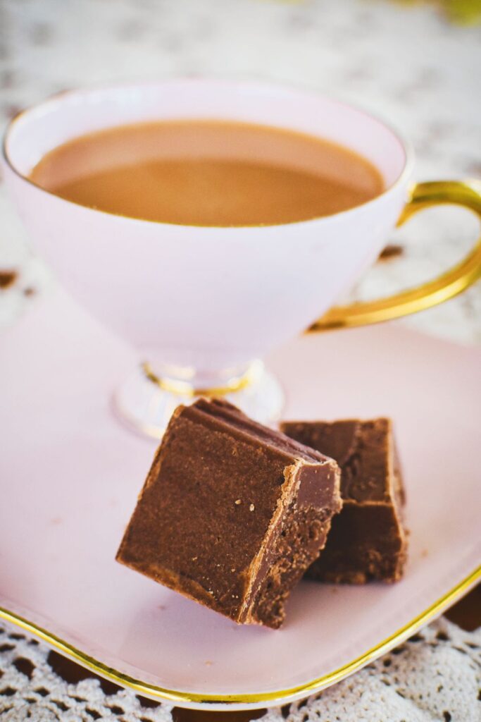 chocolate fudge on pate with cup of tea in background.