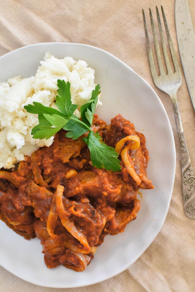 sausage casserole served on a plate with mashed potato.