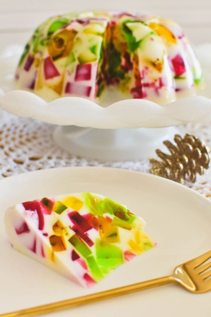 broken glass jelly on cake stand with slice on plate in foreground.