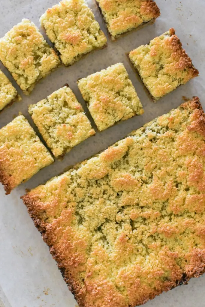 cutting coconut slice with raspberry jam into squares.