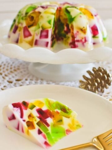 broken glass jelly on cake stand with slice on plate in foreground.