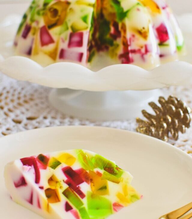 broken glass jelly on cake stand with slice on plate in foreground.