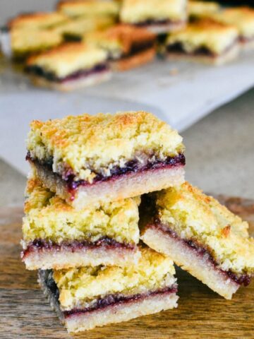 raspberry coconut slice stacked on board.