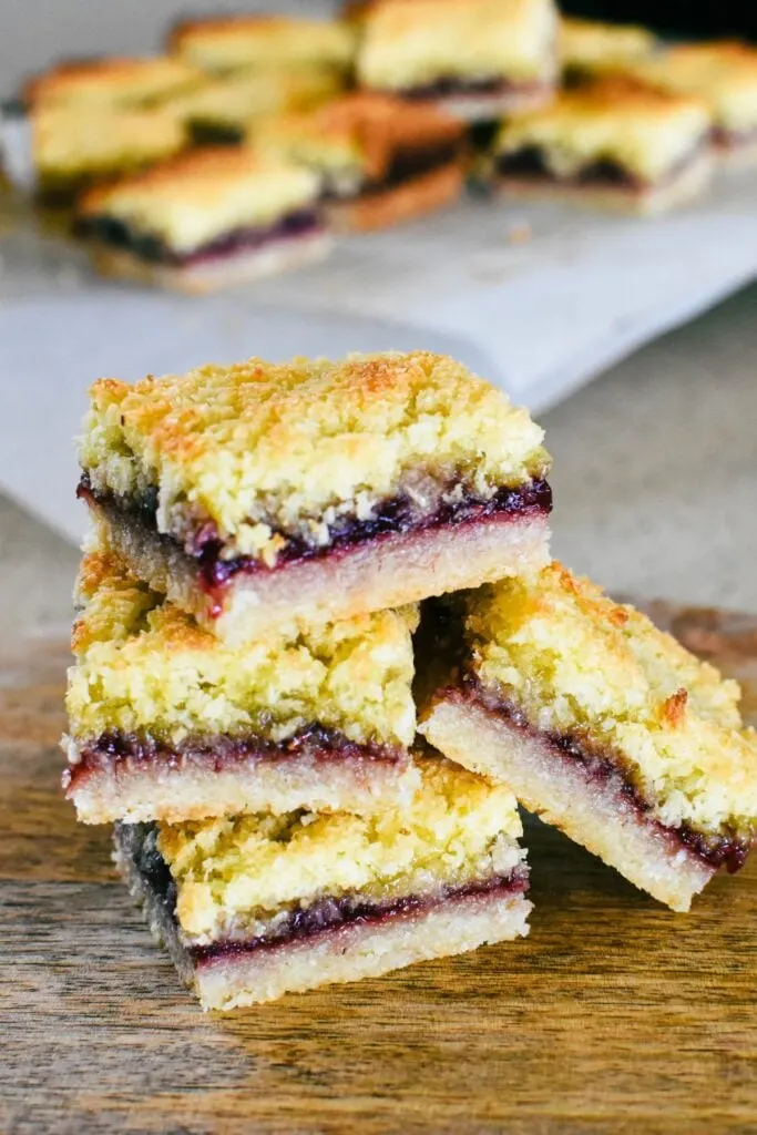 raspberry coconut slice stacked on board.