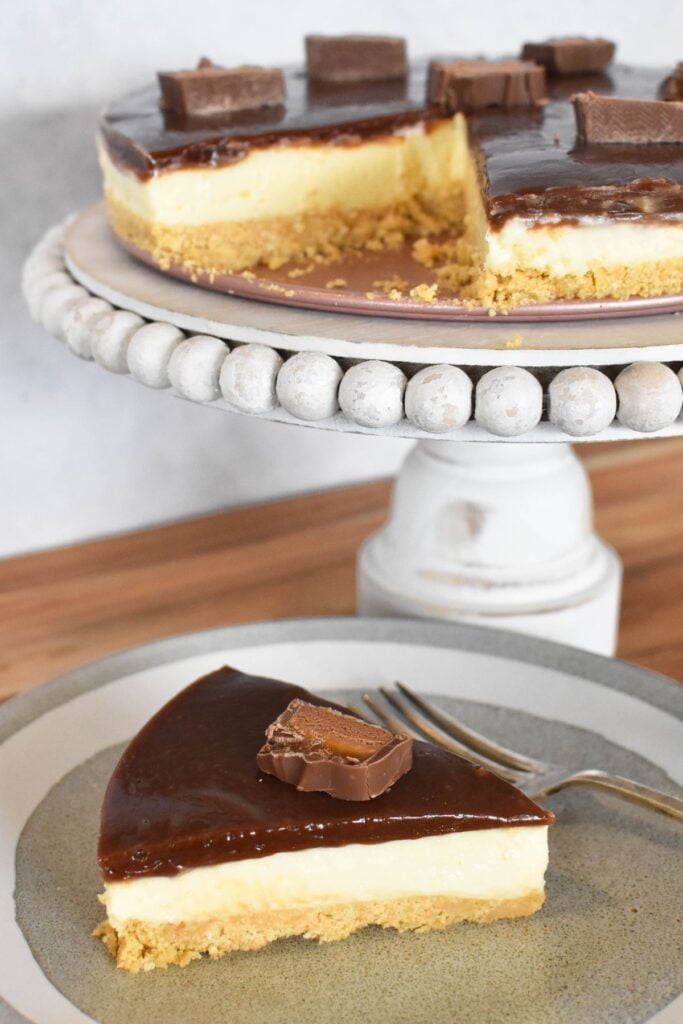 Mars Bar cheesecake slice with whole cheesecake in background.