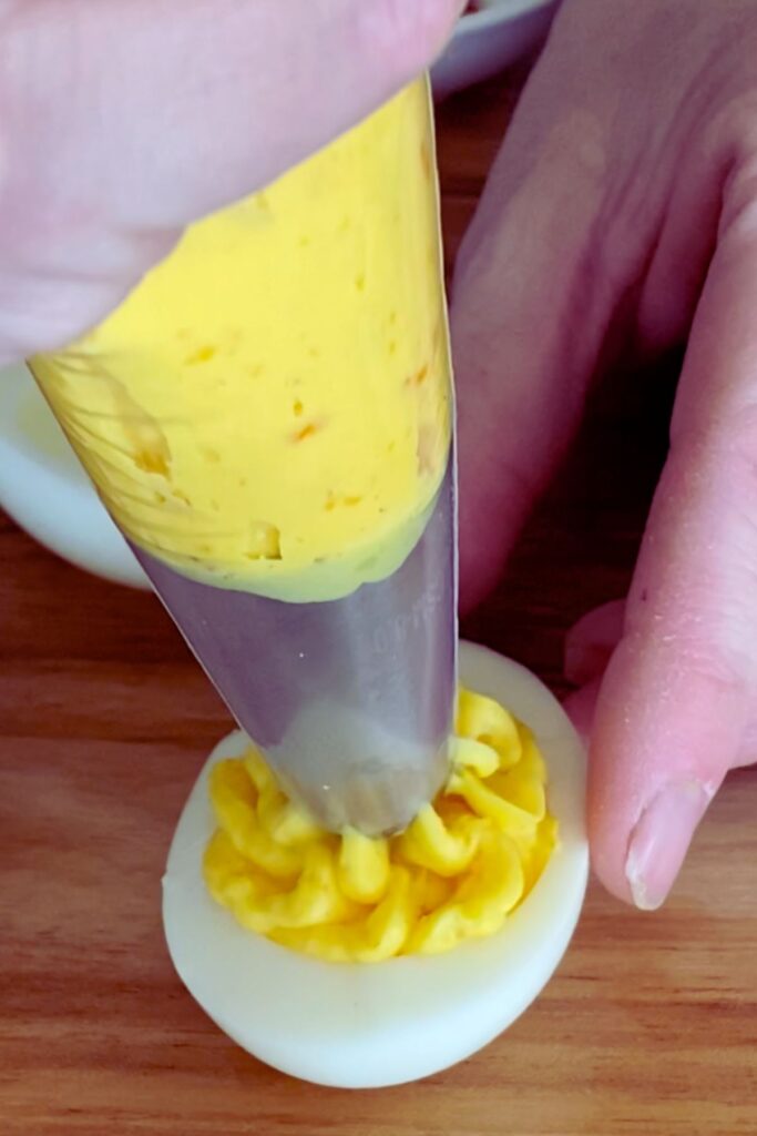 piping yolk mixture into boiled egg.