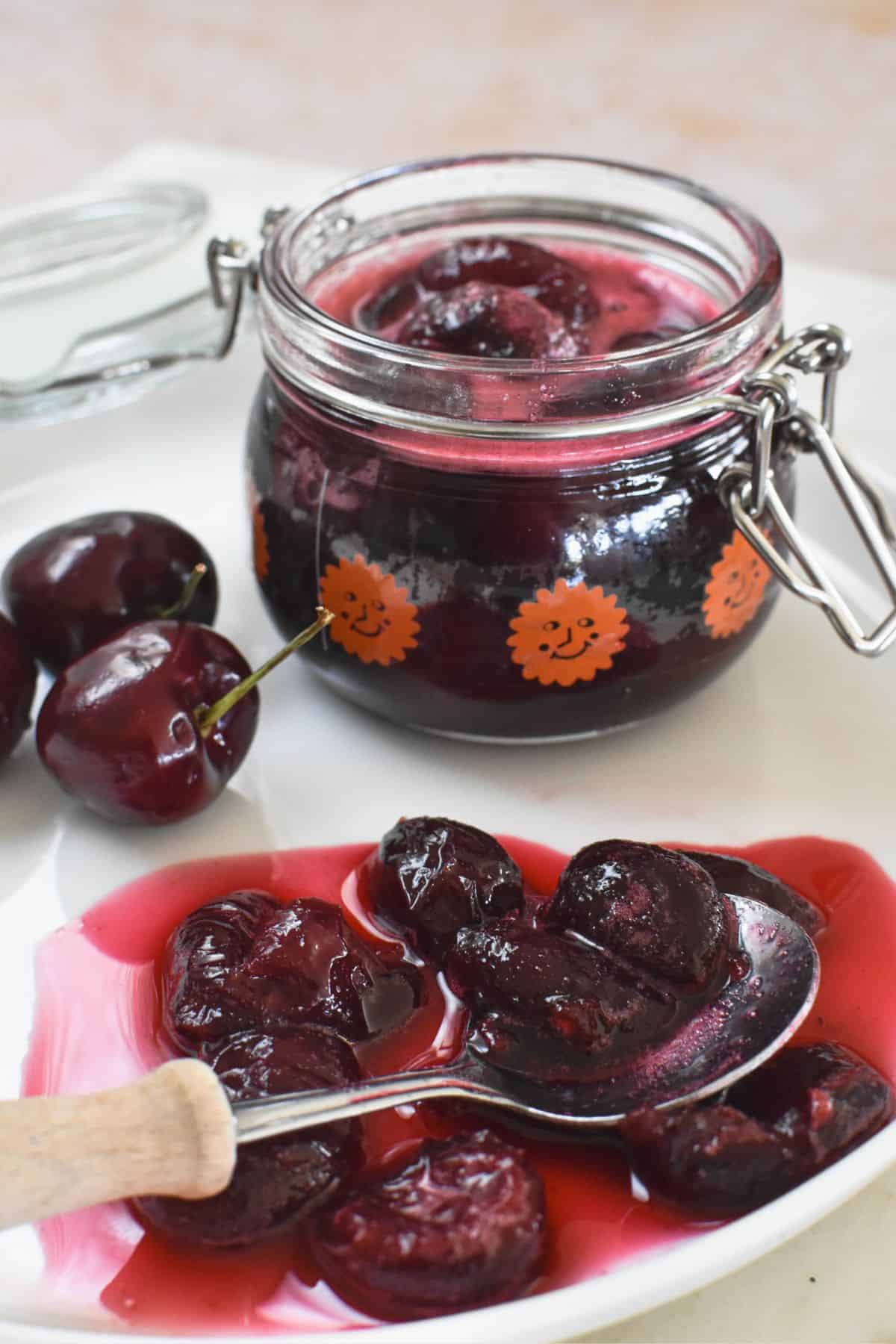 cherry compote on plate with jar in background.