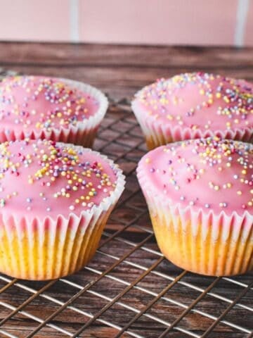 Patty Cakes, iced with a simple pink icing and decorated with pastel sprinkles.
