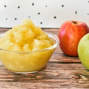 Stewed Apples in bowl with apples in background.