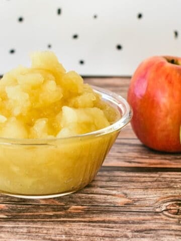 Stewed Apples in bowl with apples in background.