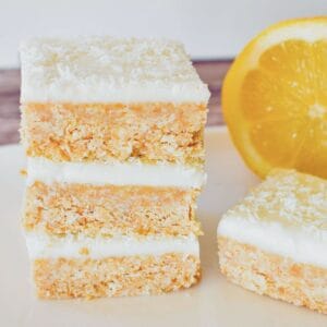 No Bake Lemon slice stacked on plate with lemon in background.