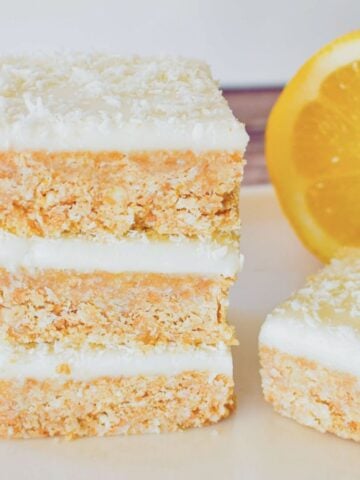 No Bake Lemon slice stacked on plate with lemon in background.