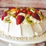 Pavlova decorated with cream and fruit.
