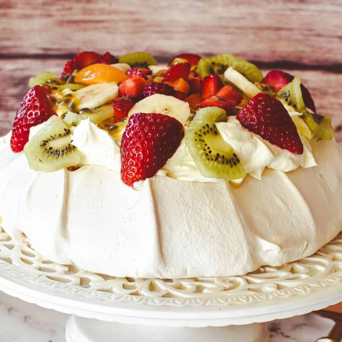 Pavlova decorated with cream and fruit.