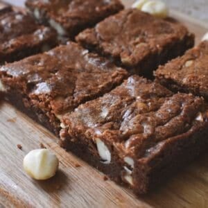 Chocolate Macadamia Brownies in squares on wooden serving board.