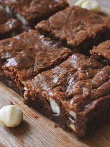 Chocolate Macadamia Brownies in squares on wooden serving board.
