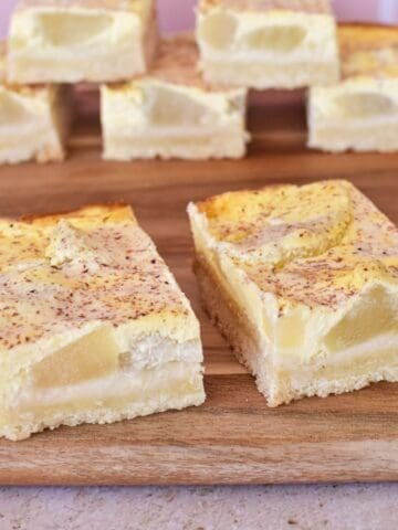 Apple and Sour cream Slice on wooden serving board.